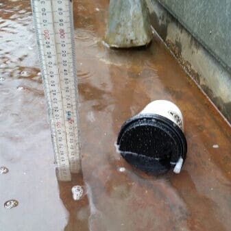 A used coffee cup floating in the water that floods a box gutter
